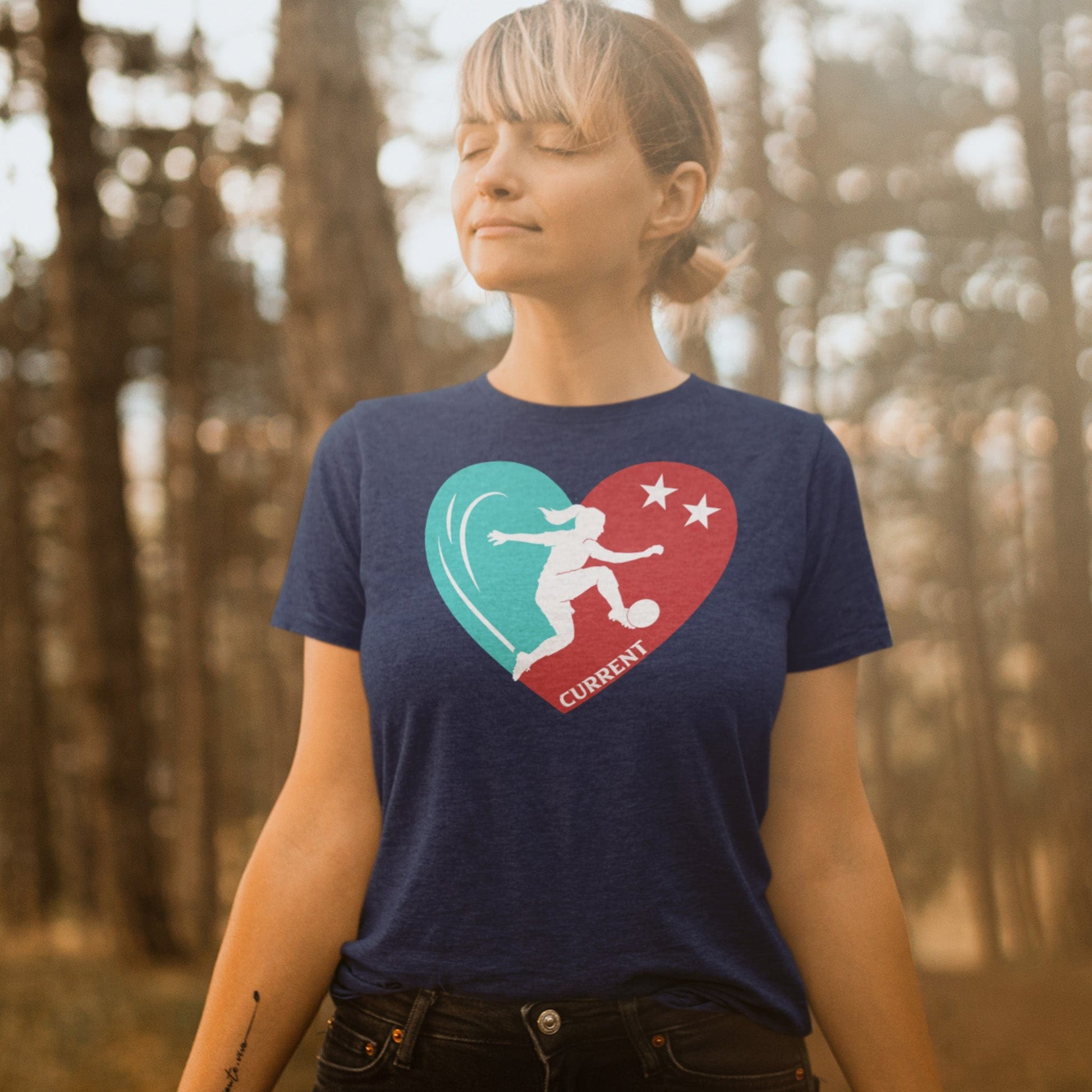 KC Swag Kansas City Current PLAYER HEART on heather navy unisex t-shirt worn by female model standing in warm forest
