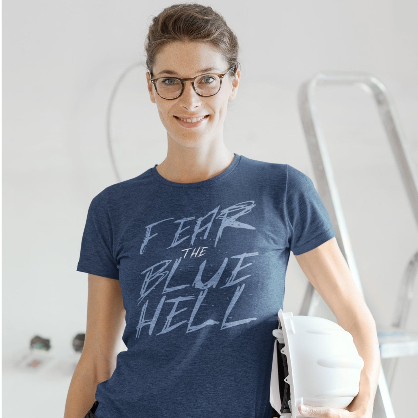 KC Swag Sporting Kansas City light blue white FEAR THE BLUE HELL on heather navy t-shirt worn by female model holding hard-hat in construction setting