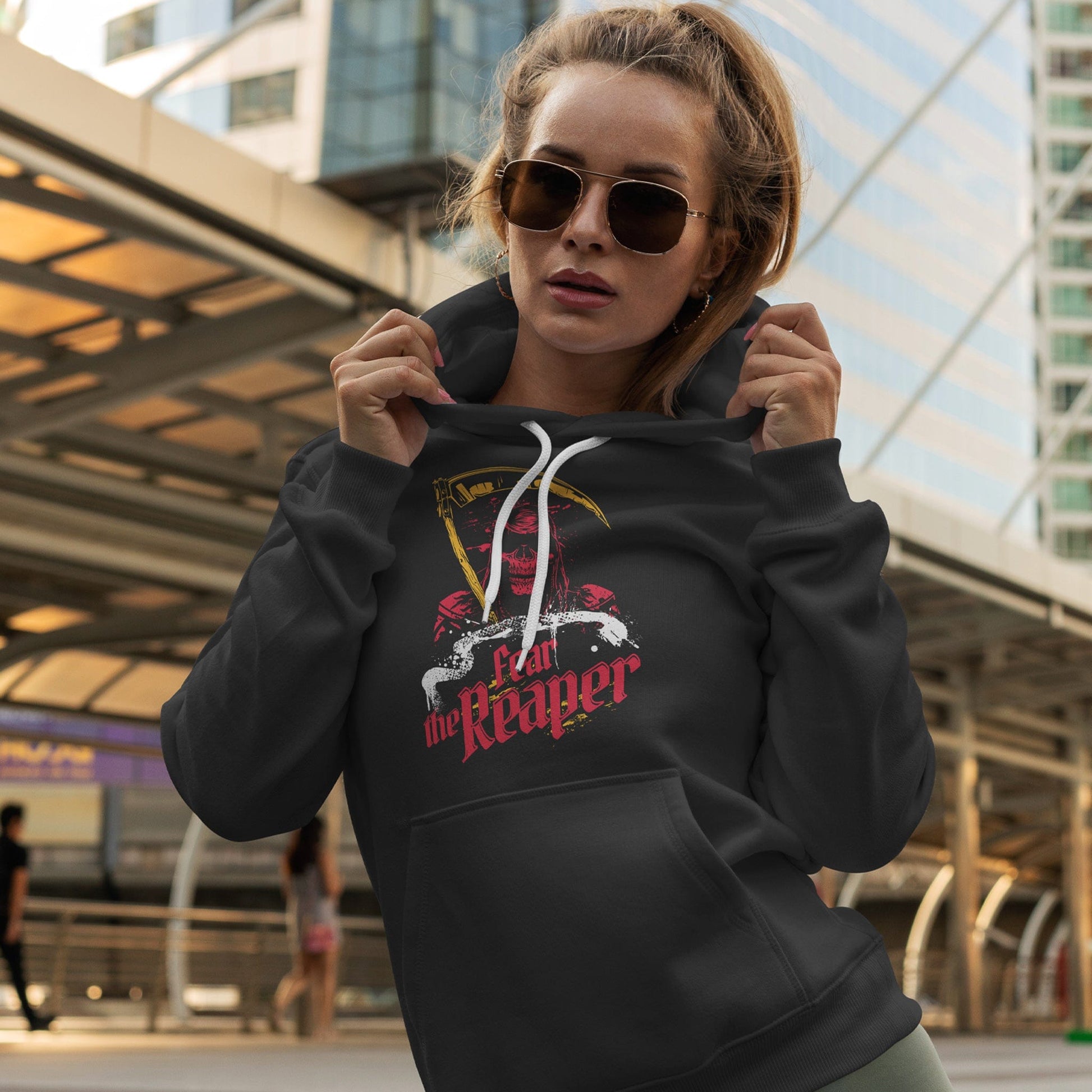 KC Swag Kansas City Chiefs FEAR THE REAPER on black fleece pull-over hoodie worn by female model in front of public transportation terminal