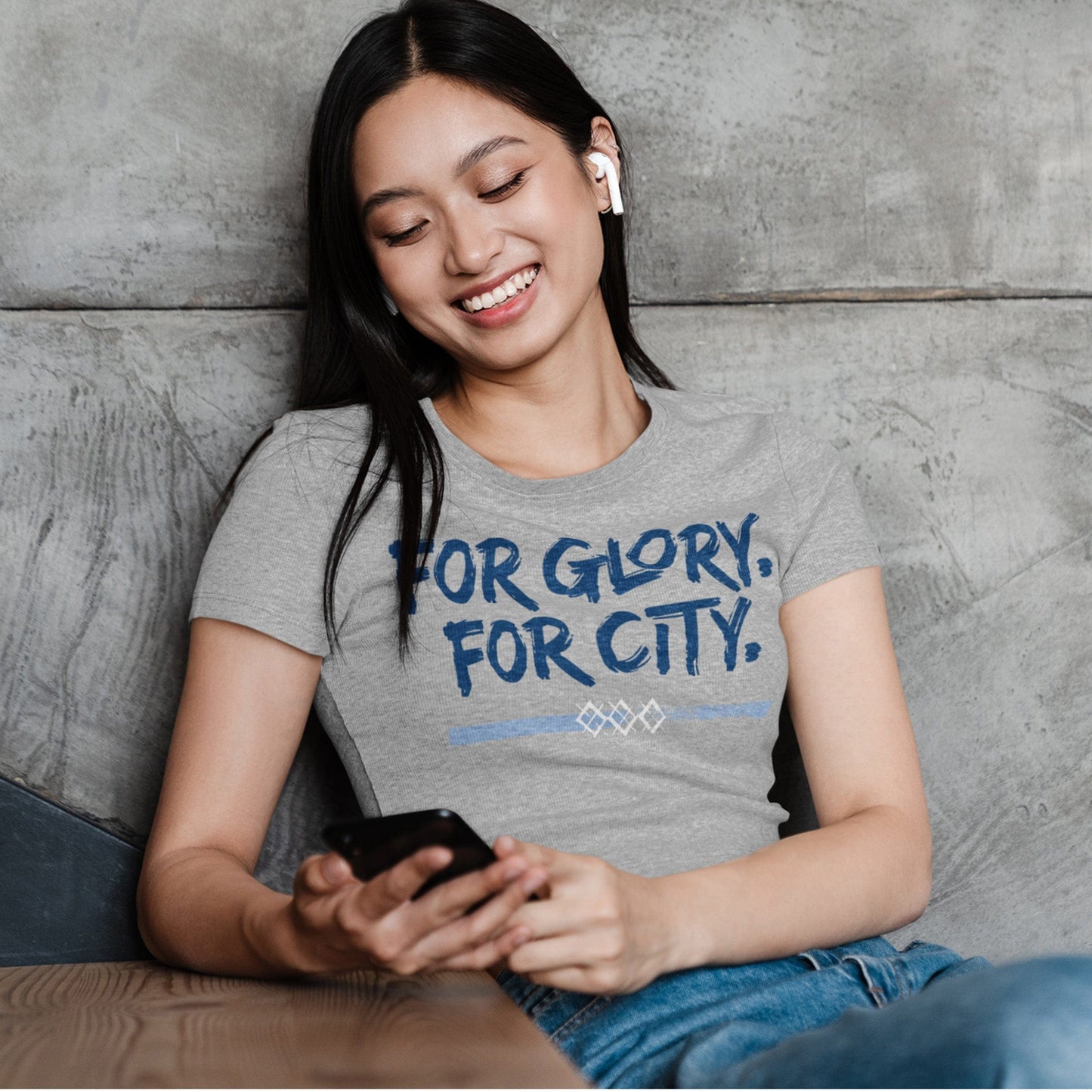 KC Swag Sporting Kansas City navy, powder, white FOR GLORY FOR CITY on athletic heather grey unisex t-shirt worn by female model sitting at table against a concrete wall