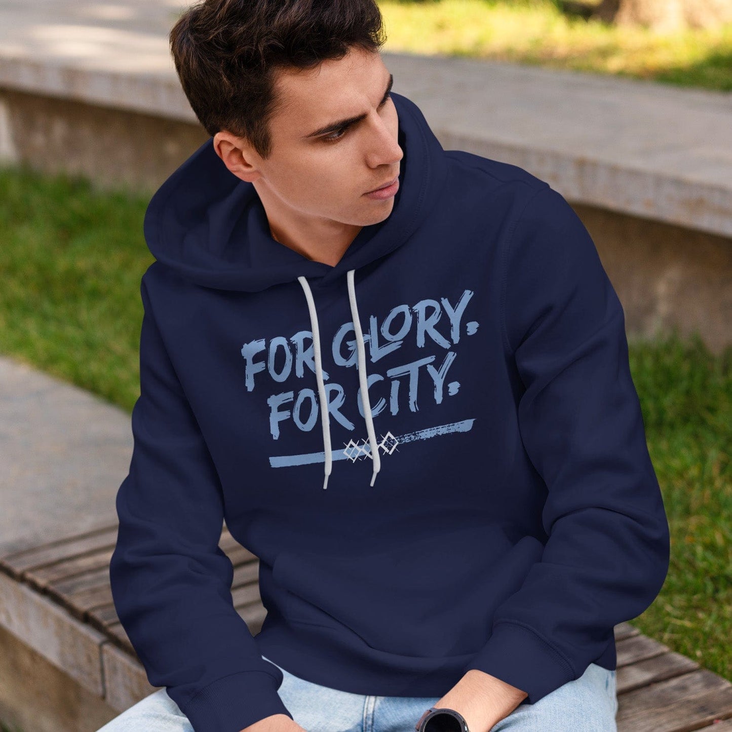 KC Swag Sporting Kansas City navy, powder, white FOR GLORY FOR CITY on navy pullover fleece hoodie worn by male model sitting on bench in public park