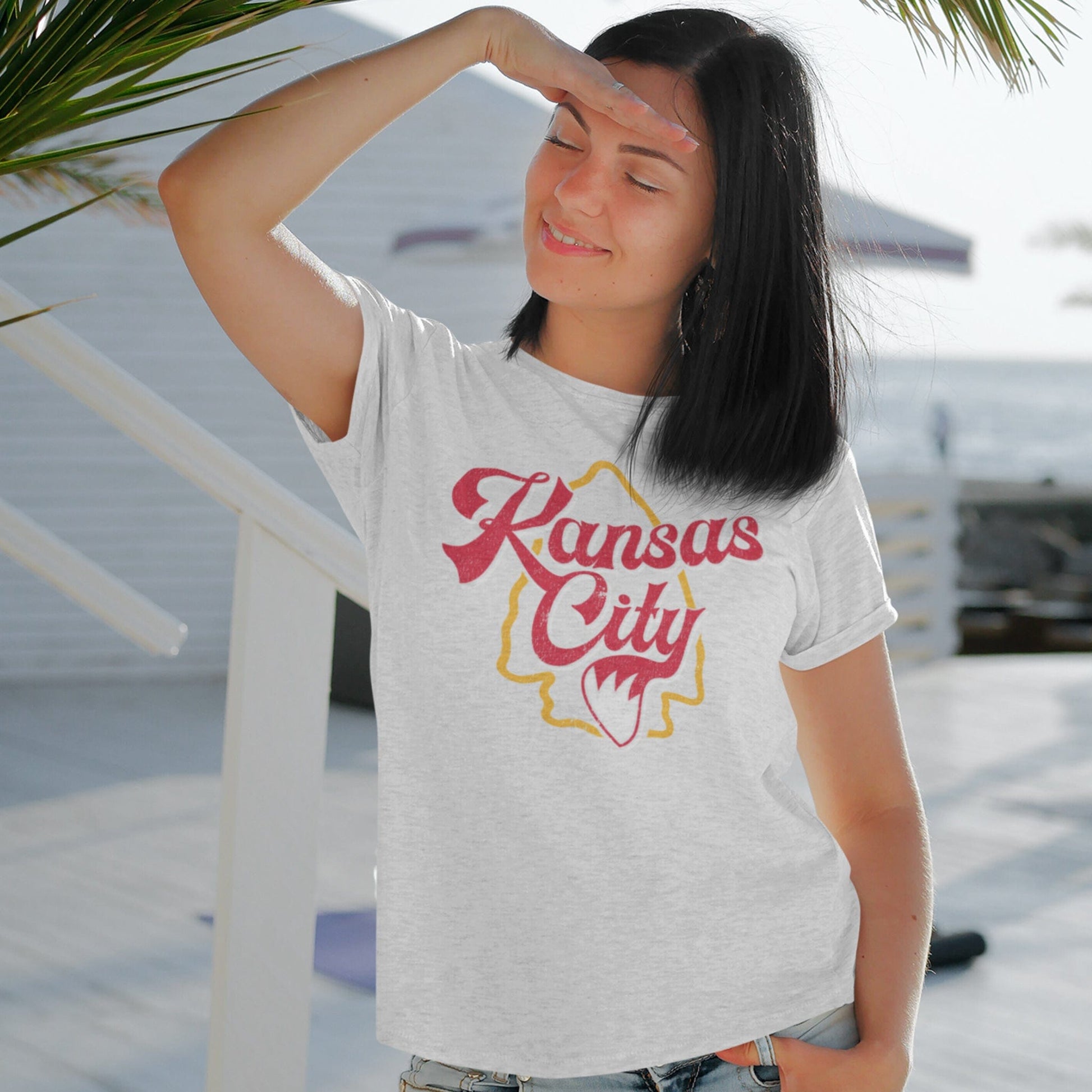 KC Swag Kansas City Chiefs red/yellow KANSAS CITY (with foxtail) with arrowhead graphic on ash t-shirt worn by female model in open-air patio