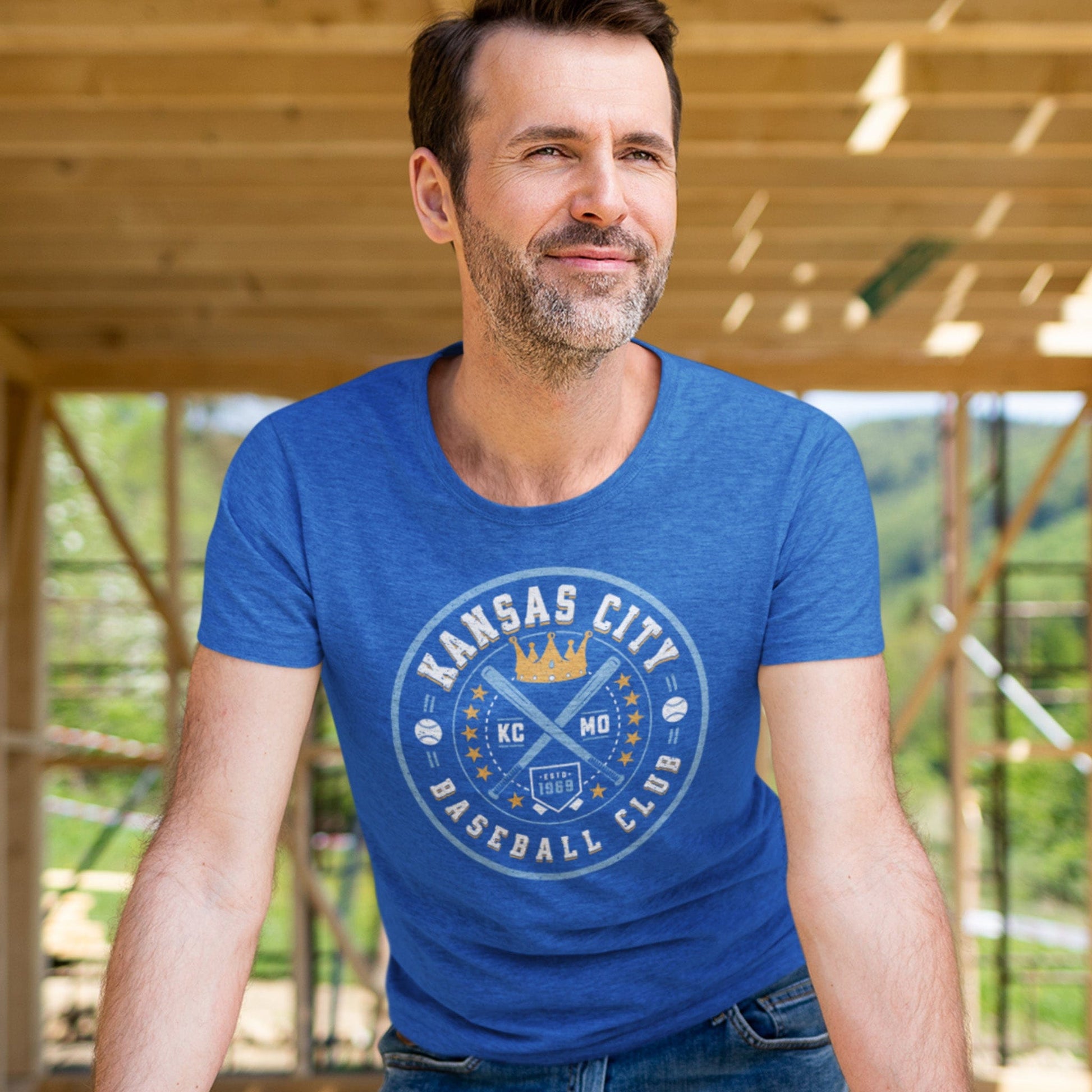 KC Swag Kansas City Royals blue, gold, white KC BASEBALL CLUB on heather royal blue unisex t-shirt worn by male model standing in home construction zone