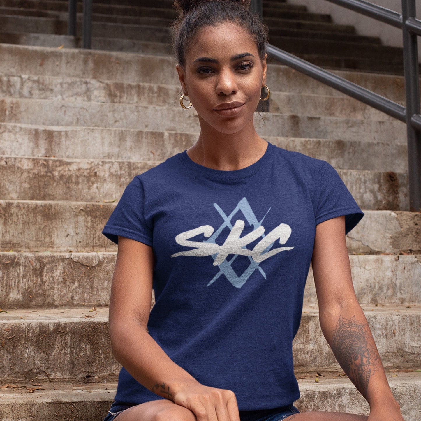 KC Swag Sporting Kansas City PAINTED SKC DIAMOND on heather navy unisex t-shirt worn by female model sitting on stained concrete stairs