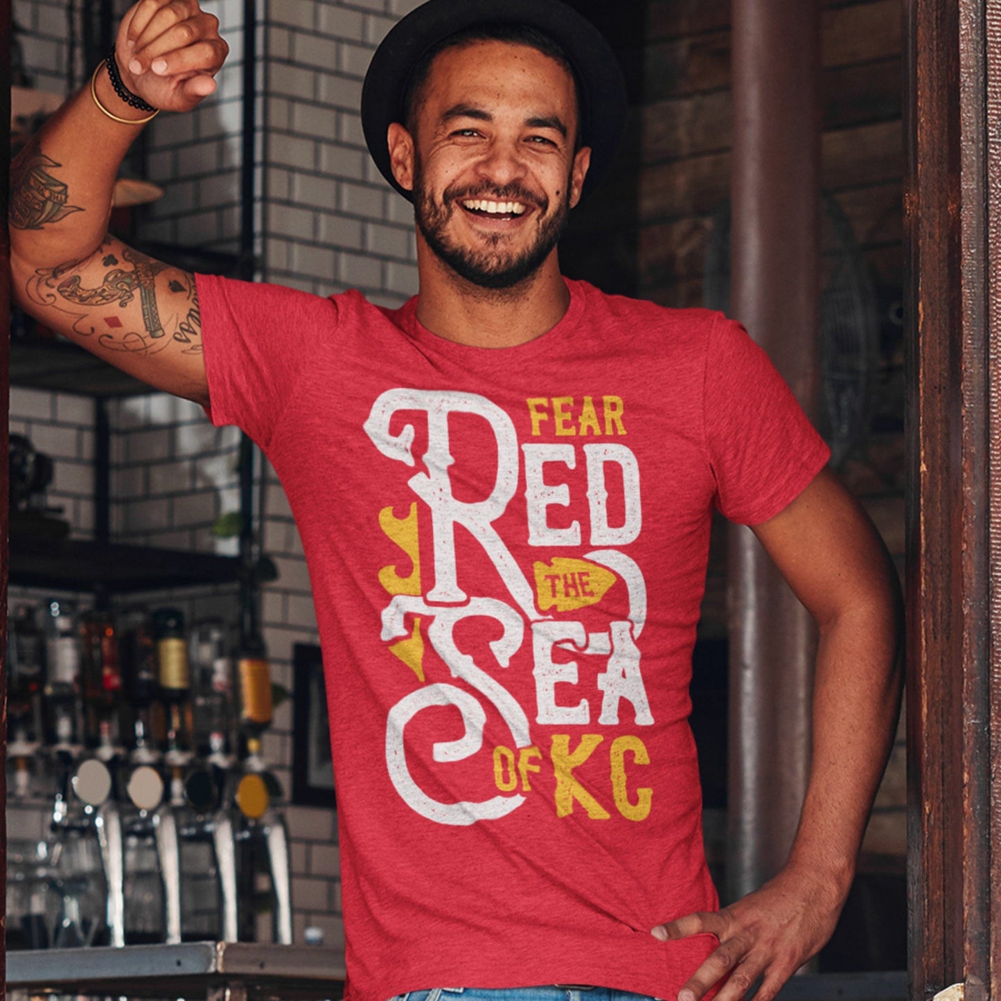 KC Swag Kansas City Chiefs SEA OF RED on heather red t-shirt worn by male model standing in pub doorway