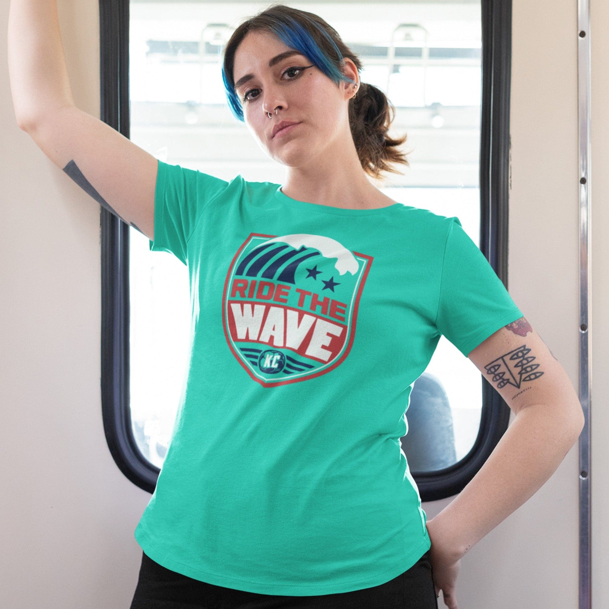 KC Swag Kansas City Current RIDE THE WAVE on teal unisex t-shirt worn by female model standing in street car