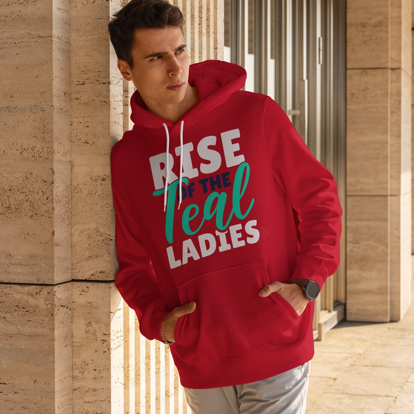 KC Swag Kansas City Current TEAL LADIES RISE on red fleece pullover hoodie worn by male model leaning against a stone wall in outdoor plaza