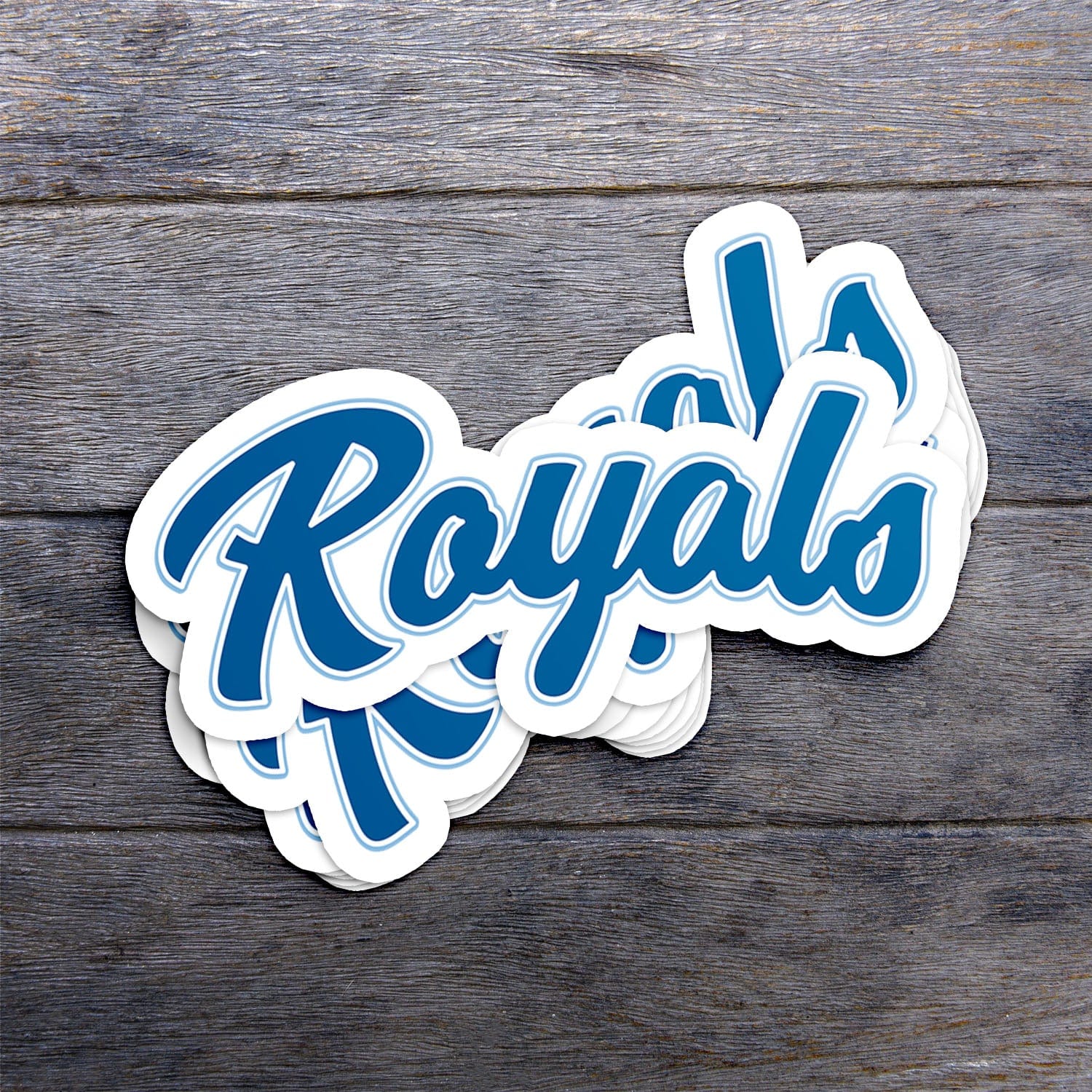 KC Swag Kansas City Royals blue, powder Royals Scrip vinyl die cut decal sticker stack on dark wood table