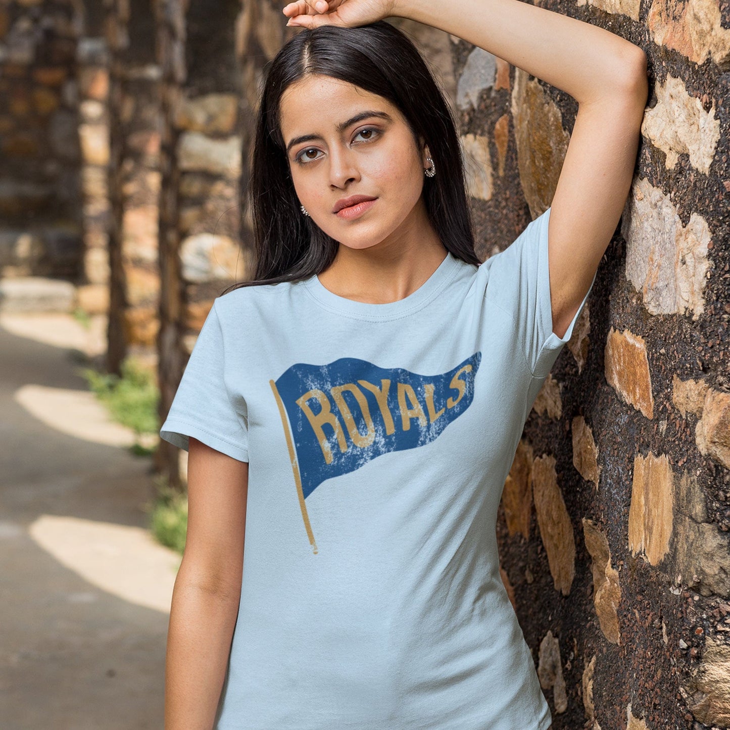 KC Swag Kansas City Royals blue/gold ROYALS PENNANT on lite blue t-shirt worn by female model leaning against stone wall