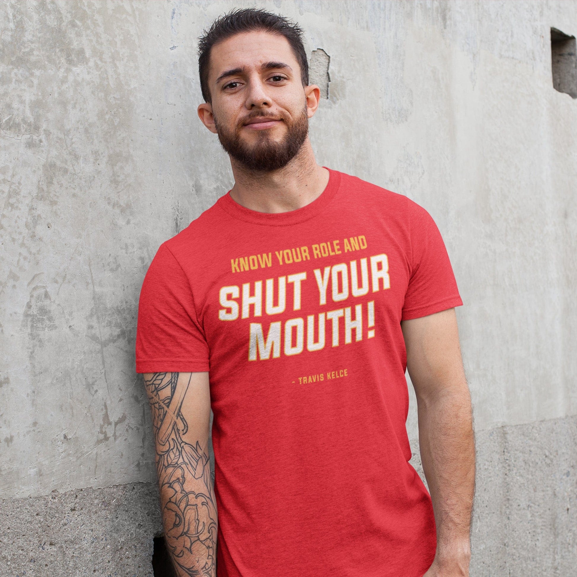 KC Swah Kansas City Chiefs red, yellow, white SHUT YOUR MOUTH on heather red unisex t-shirt worn by male model standing against concrete wall