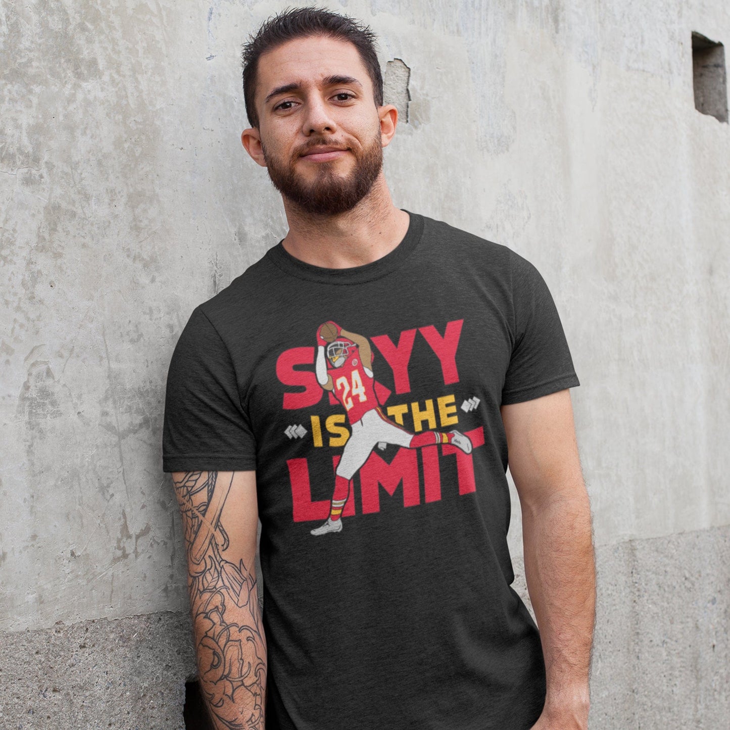 KC Swag Kansas City Chiefs SKYY IS THE LIMIT with football player graphic on dark heather grey t-shirt worn by male model against concrete wall