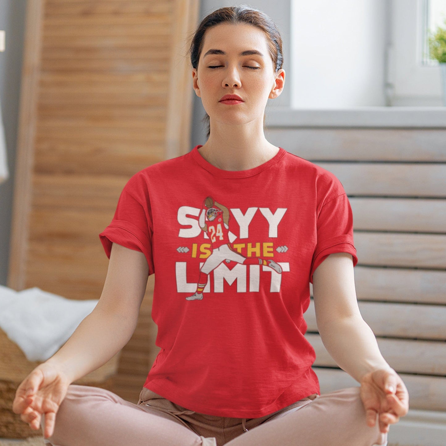 KC Swag Kansas City Chiefs SKYY IS THE LIMIT with football player graphic on heather red t-shirt worn by female model meditating on the floor