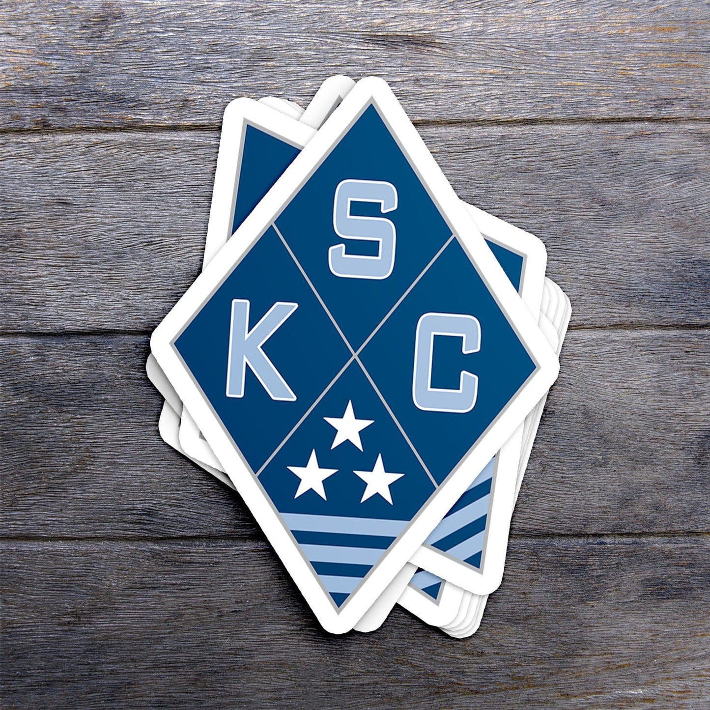 KC Swag Sporting Kansas City powder, navy, silver SKC Diamond vinyl die cut decal sticker stack on dark wood table