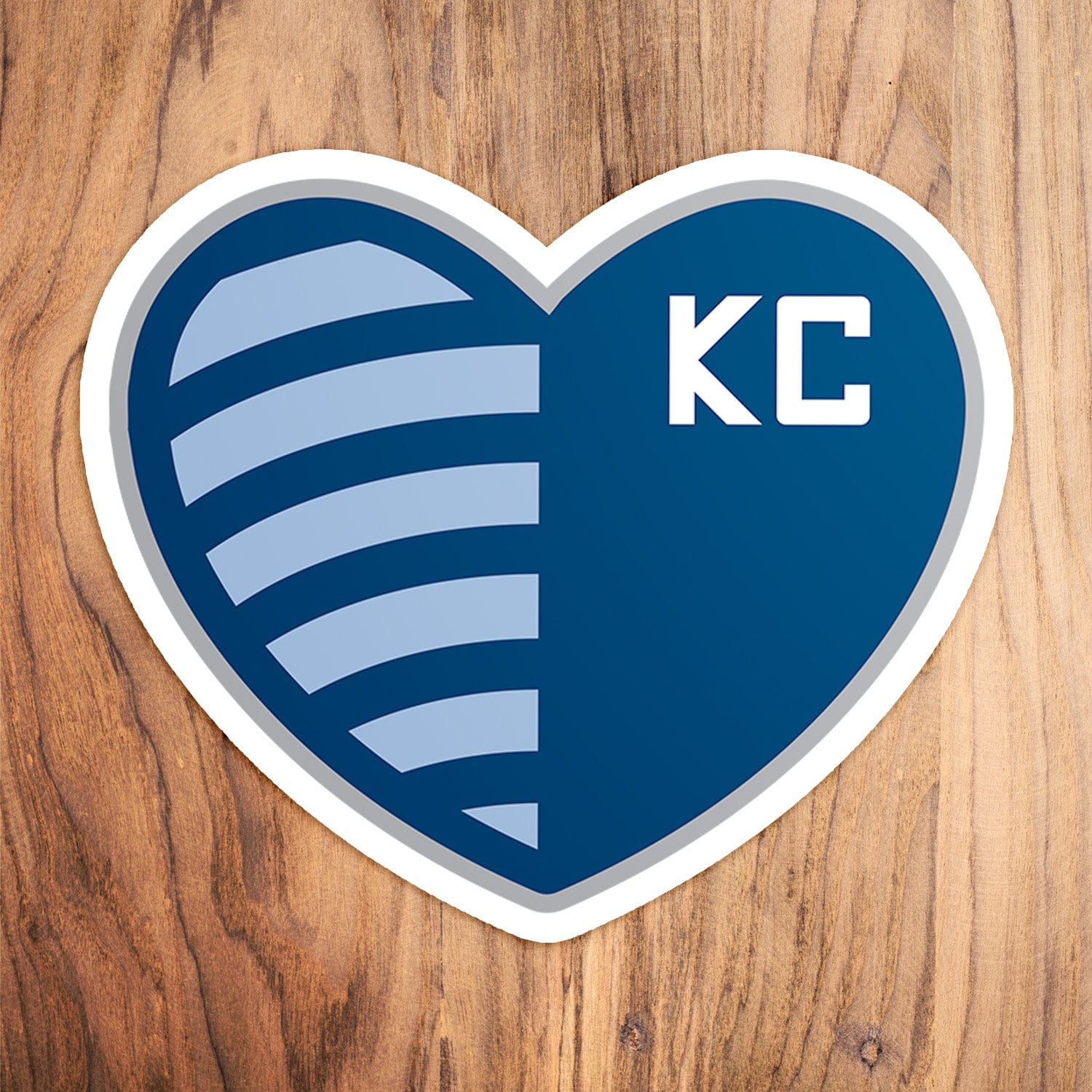 KC Swag Sporting Kansas City powder, navy, silver Shield Heart vinyl die cut decal sticker on wood table