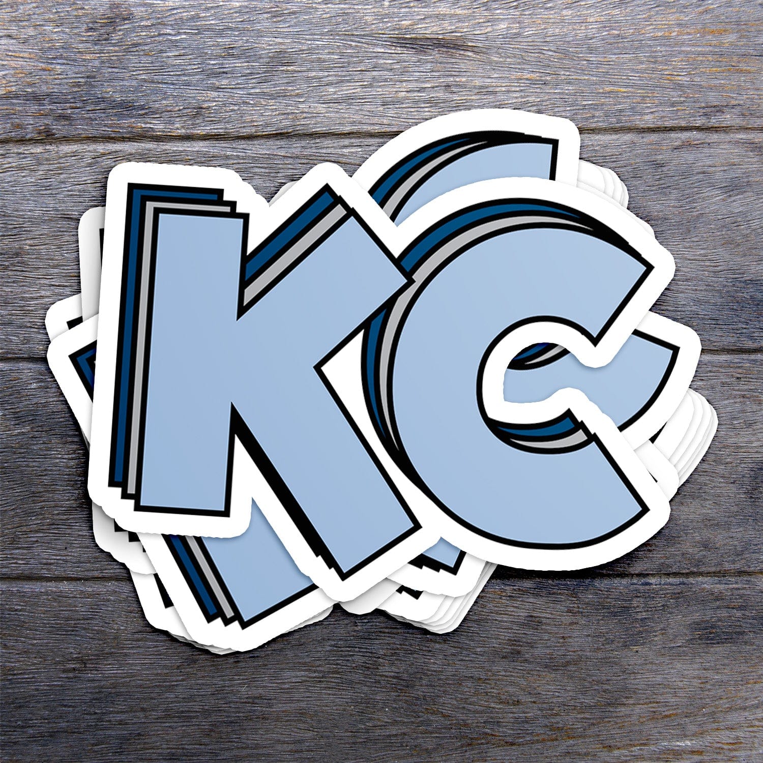 KC Swag Sporting Kansas City powder, silver, navy Stacked Powder KC vinyl die cut decal sticker stack on dark wood table