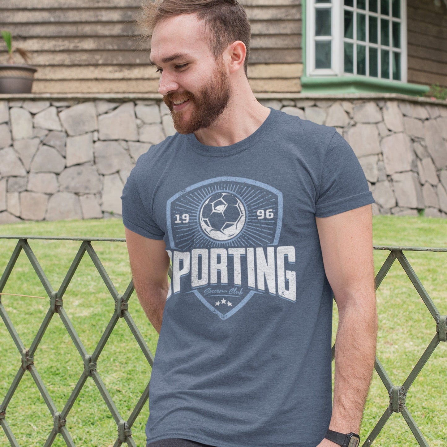 KC Swag Sporting Kansas City navy, powder, white SPORTING CLUB on on heather slate unisex t-shirt worn by male model standing against front yard fence