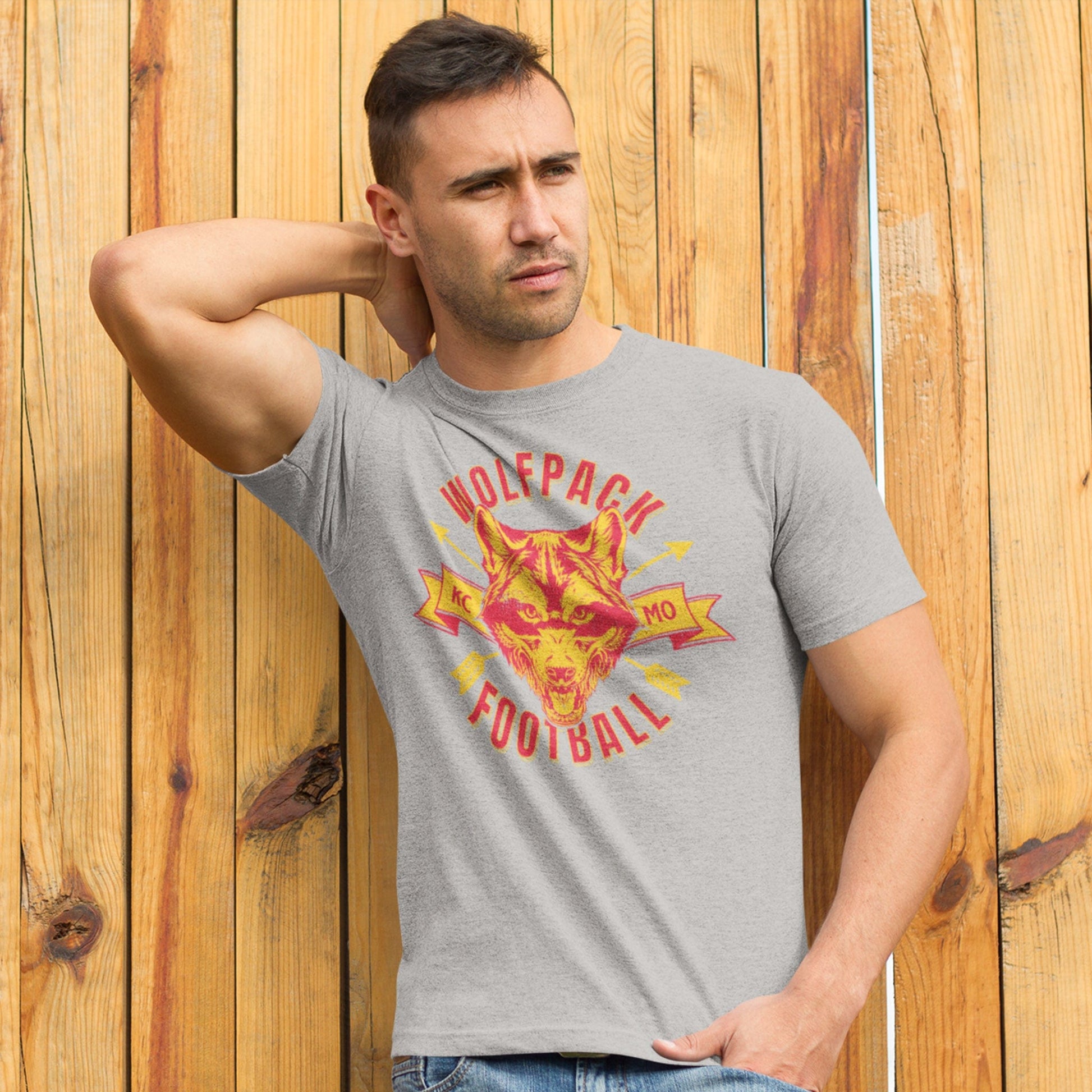 KC Swag Kansas City Chiefs WOLFPACK FOOTBALL with wolf head graphic on athletic heather grey t-shirt worn by male model against wood fence